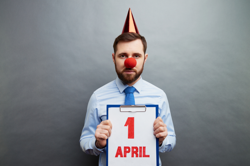 Businessman wearing clowns nose and party hat showing April fools day date