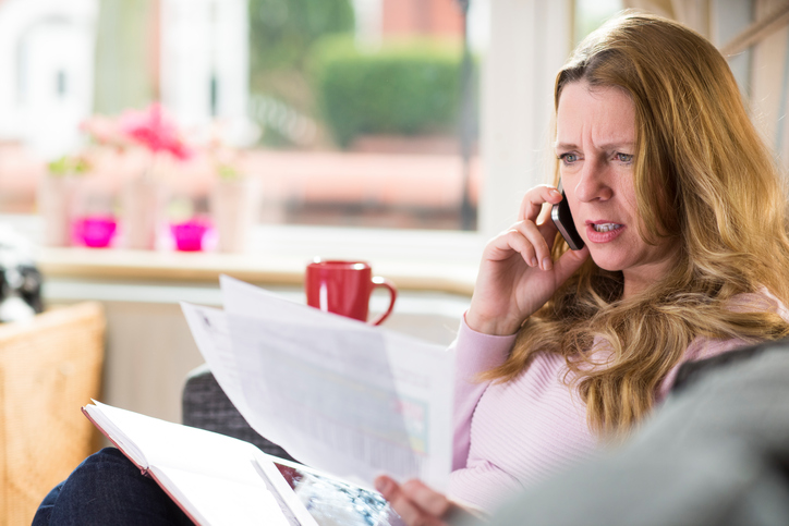 woman rings someone with a letter in her hand , she's not happy