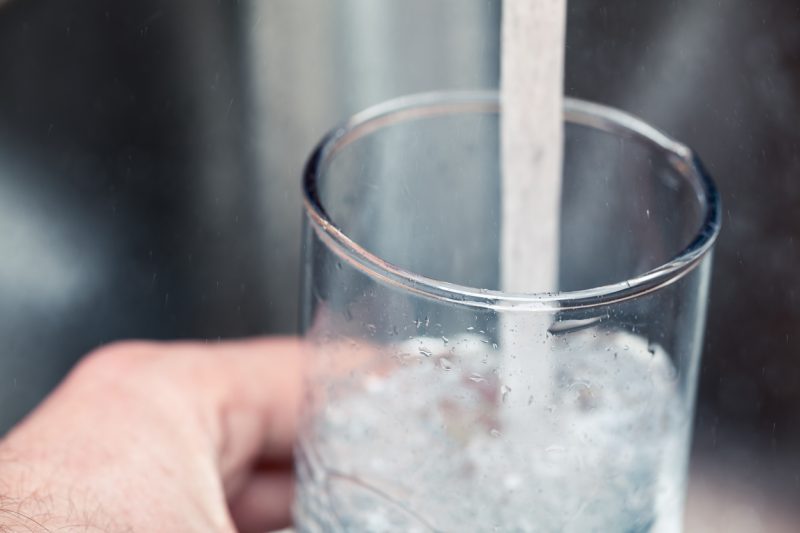 Filling up a glass with drinking water from kitchen tap