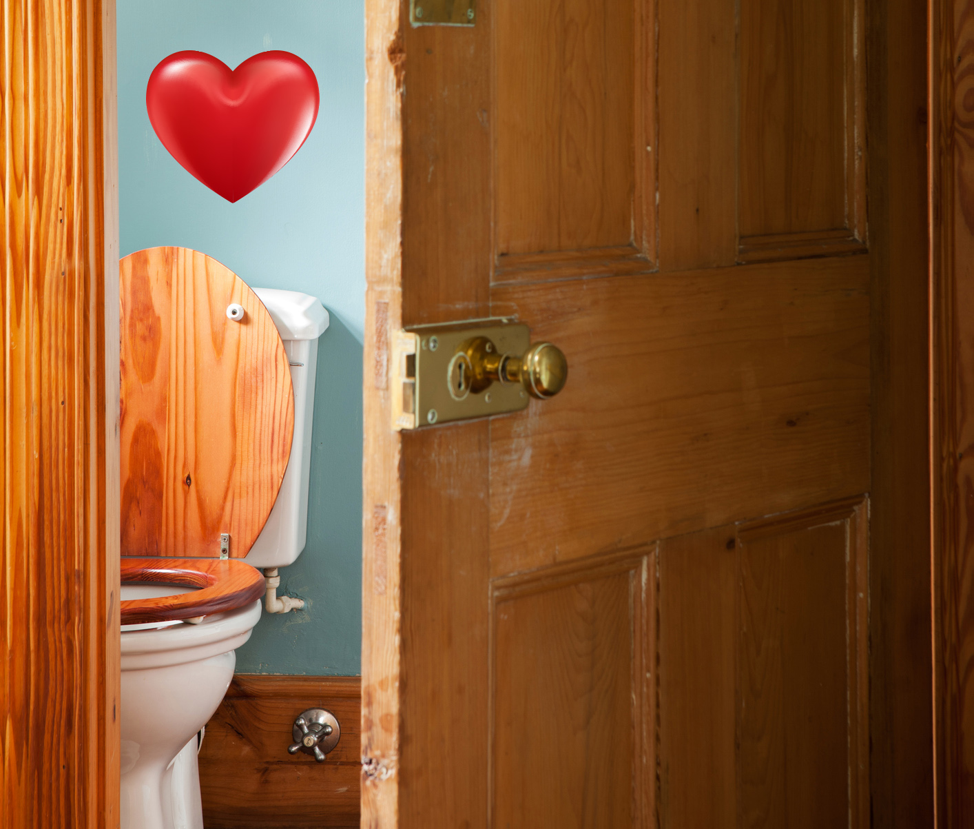 A Victorian toilet behind a half open wooden door, with love heart above