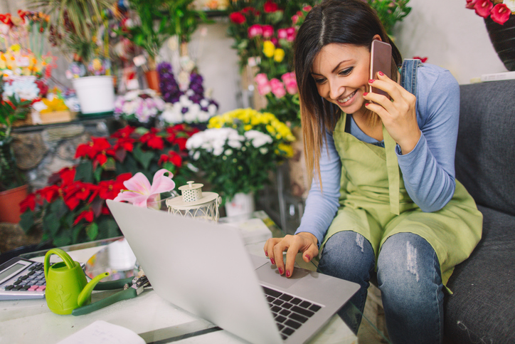 Photo of a young florist, taking orders by phone in her flower shop