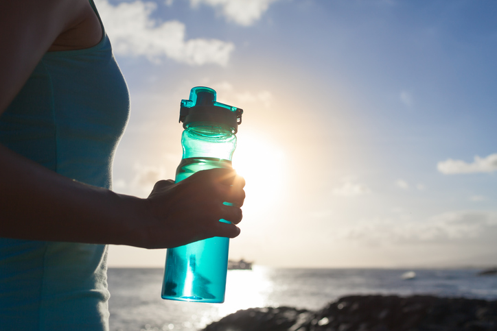 Young woman drinking water outdoors after workout.