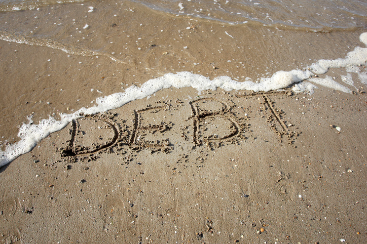 debt written on sand being washed away