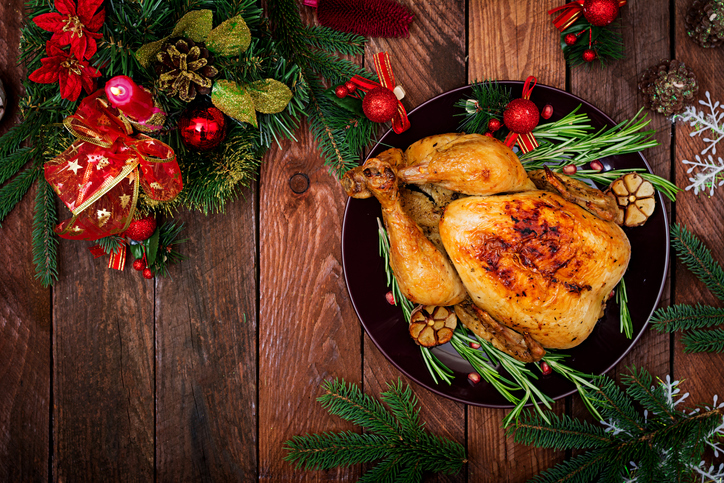 Baked turkey or chicken. The Christmas table is served with a turkey, decorated with bright tinsel and candles. Fried chicken, table. Christmas dinner. Flat lay. Top view