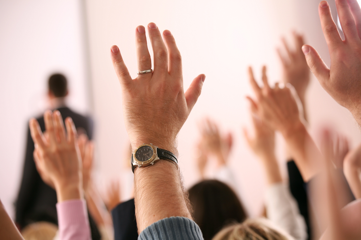 Business lecture with hands in the air.