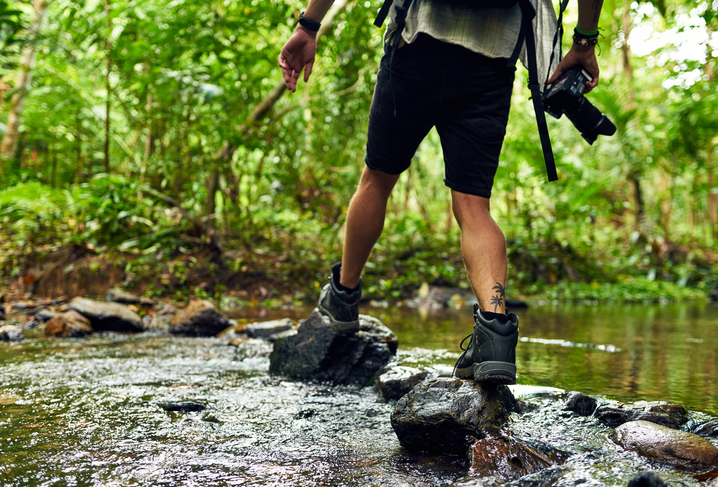 hiker crossing a stream while exploring in the woods