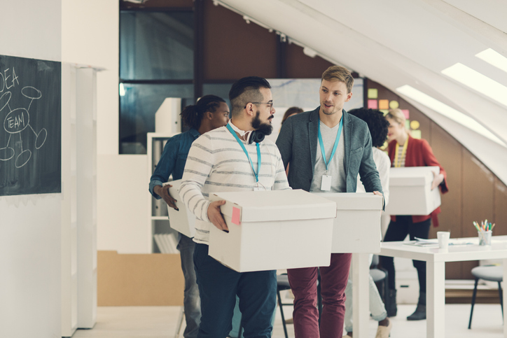 team moving to a new office holding boxes.