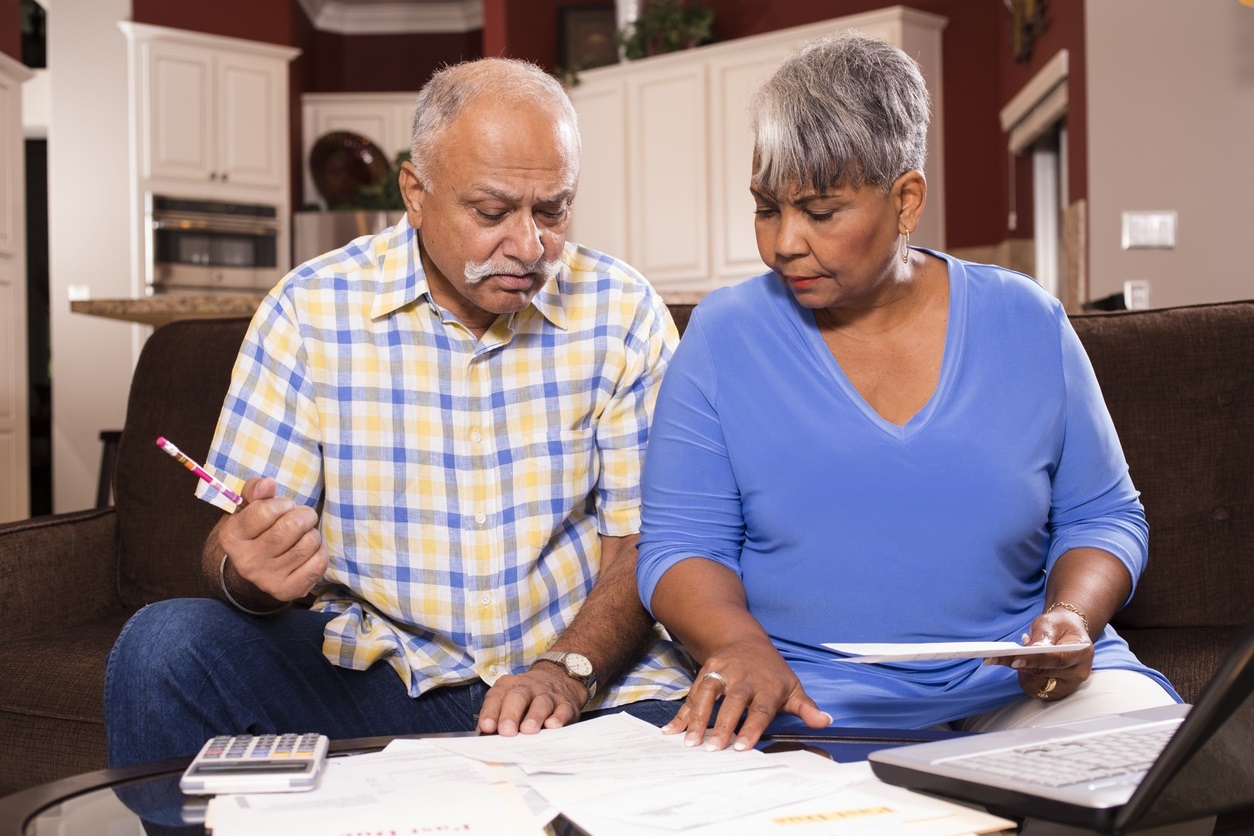 Senior couple paying monthly bills at home.