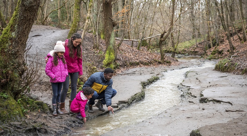 A family standing on a walkway next to a river