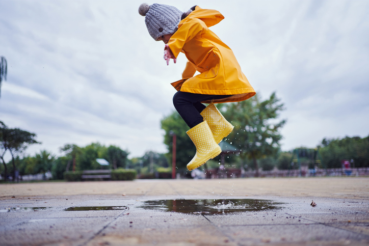 child jumping in a puddle of water