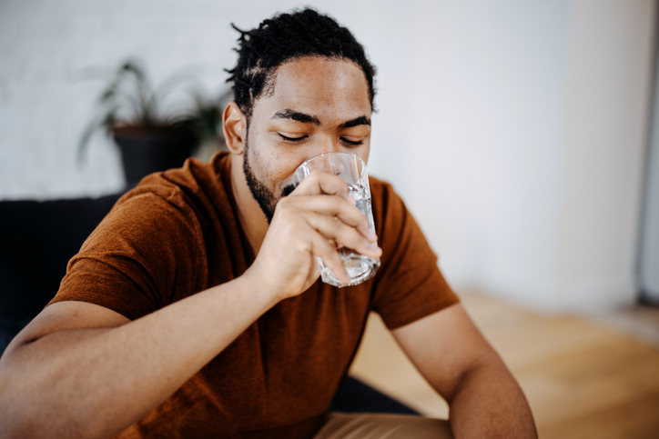 Black man drinking a glass of water at home
