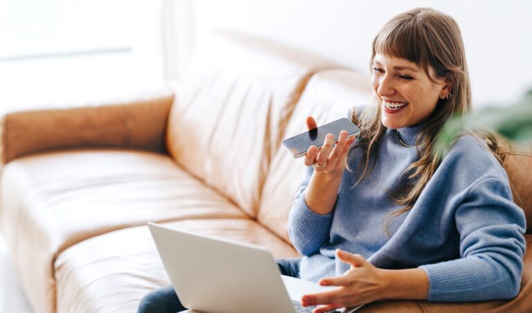 Happy young woman having a phone call while sitting on a couch. Cheerful