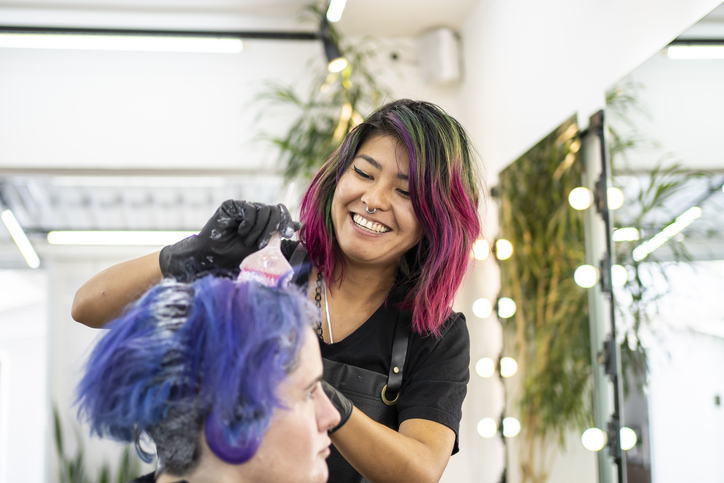 Hairdresser dyeing client's hair at hair salon