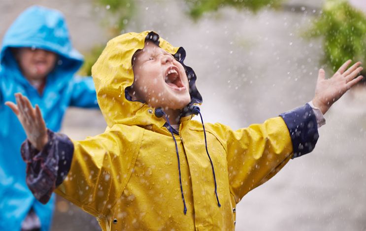 Open mouthed boy in yellow jacket in the rain