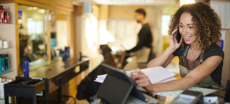 hair salon owner using digital book keeping system and chatting on the phone