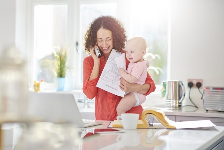 a woman in her kitchen paying a bill by phone