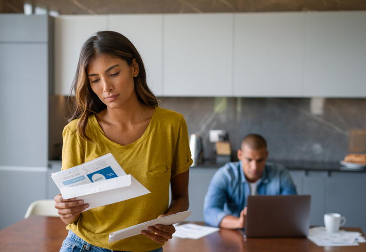 woman at home looking worried getting bills in the post