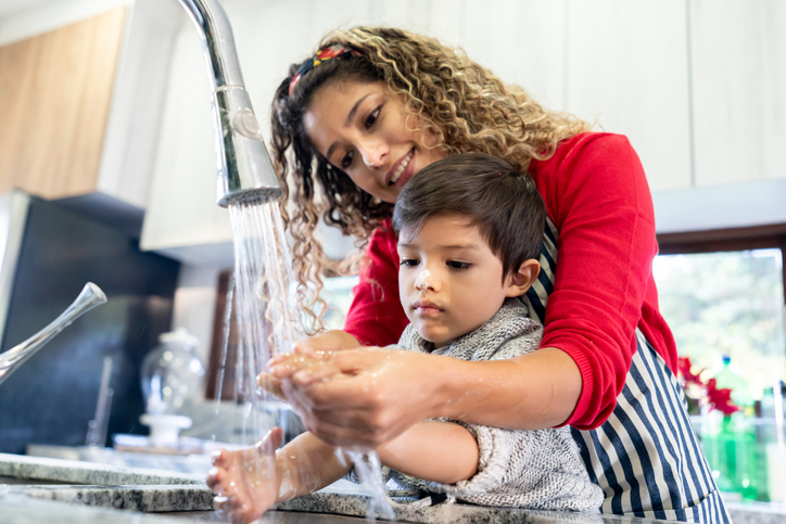 Mother helping son wash his hand in the sink