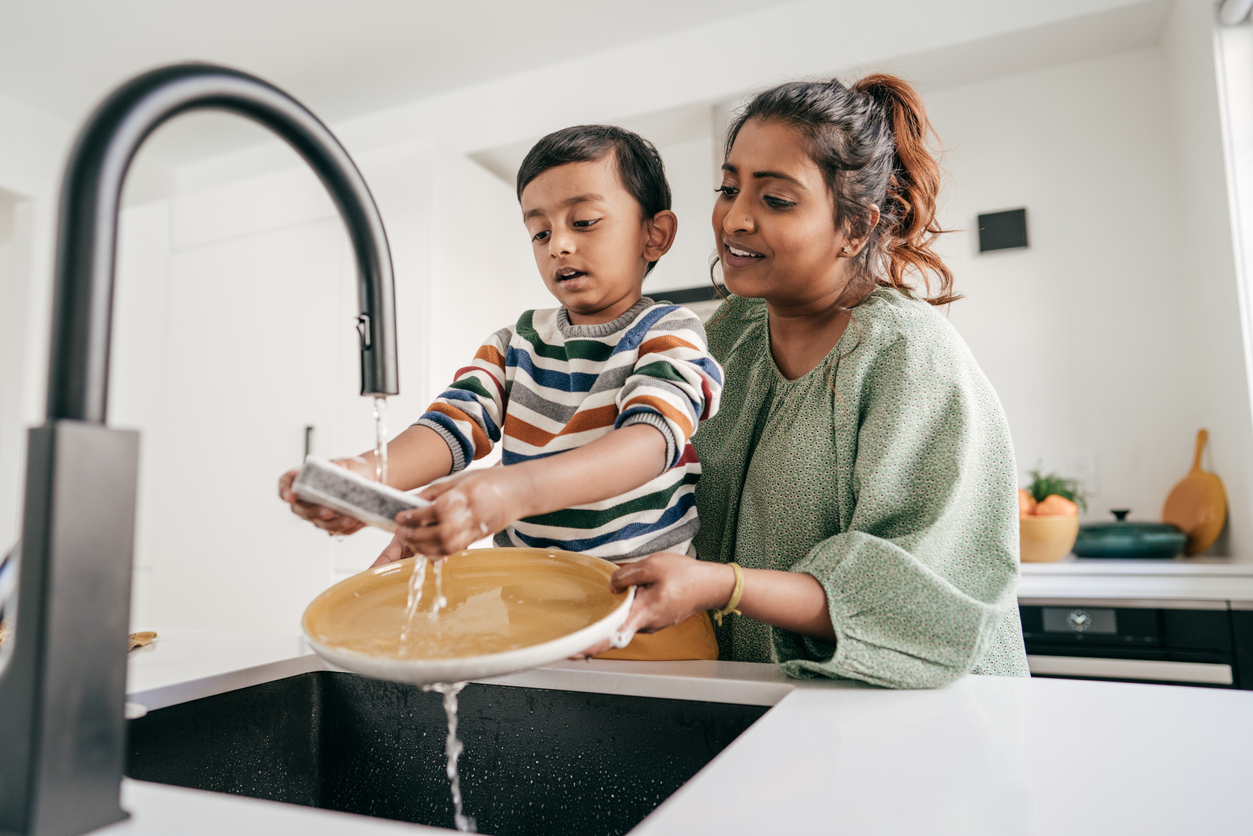 Mom and child washing dishes together