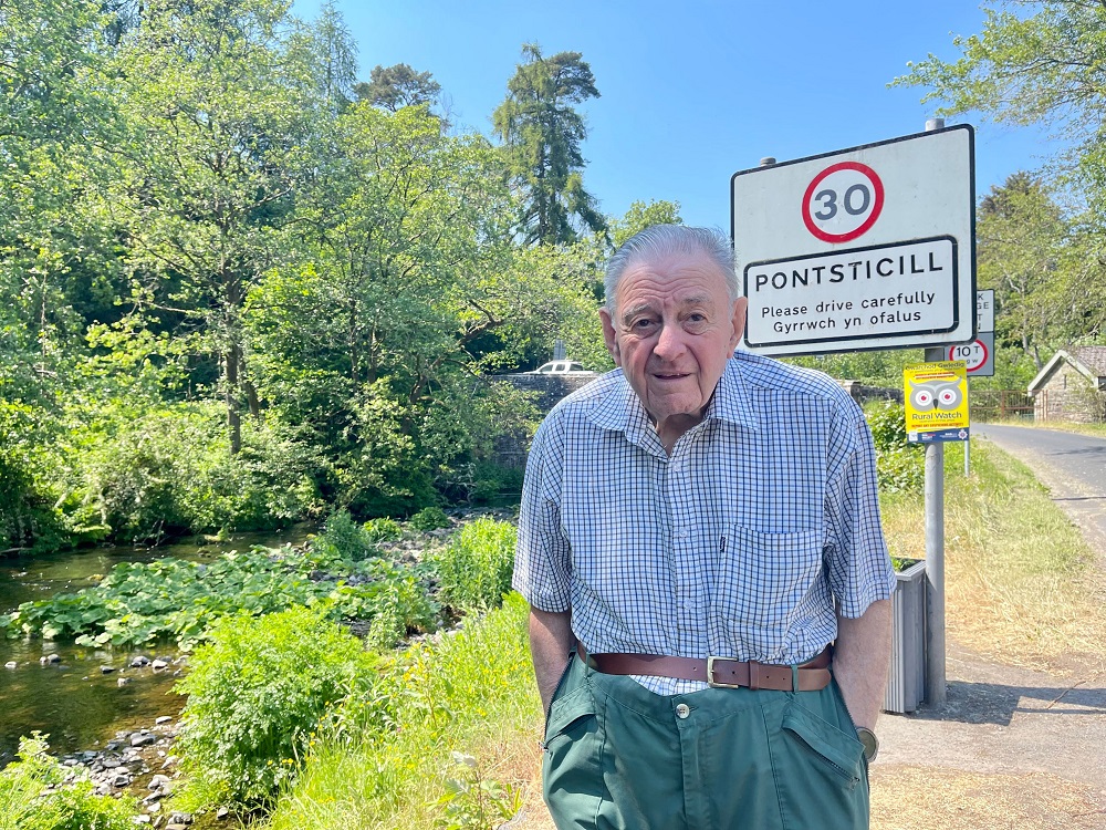 Tony Rees, an elderly man, is standing in front of a Pontsticill road sign.