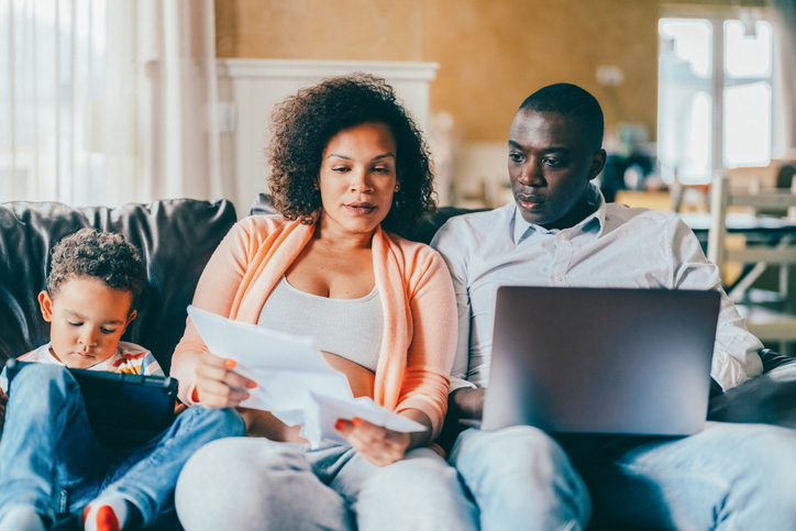 Pregnant woman with her husband at home looking at bills