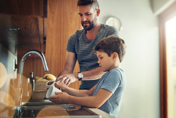 Man and boy washing cups in sink