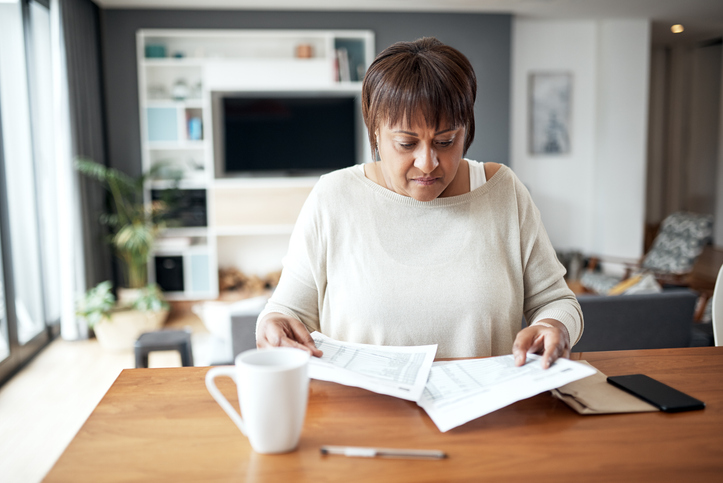 mature woman working through paperwork while sitting at home