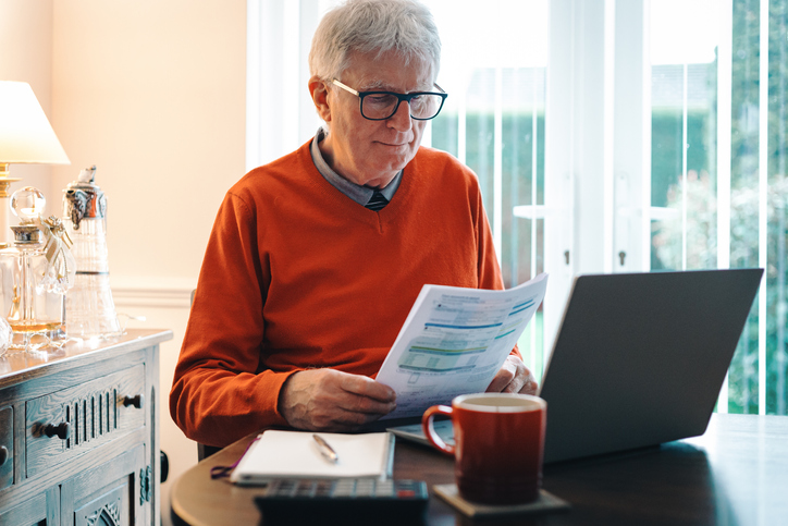 Senior caucasian man in his 70s checking his energy bills at home.
