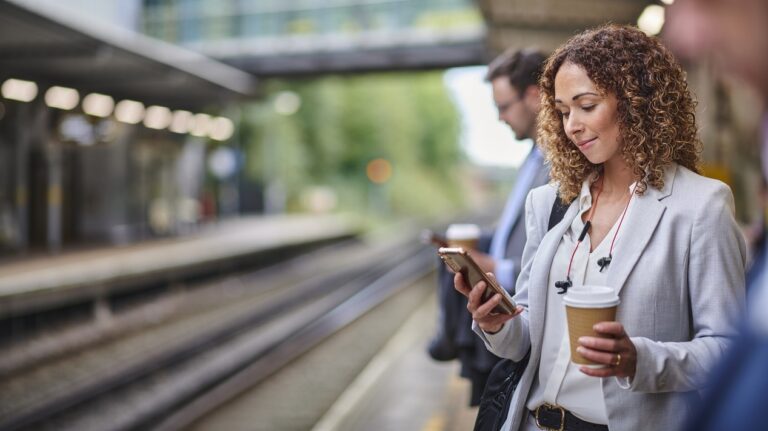 Lady looking at mobile phone, while waiting for train to work