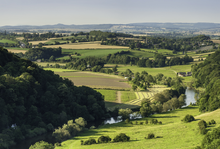 Clear blue skies over the vibrant summer foliage and green meadows of valley with the River Wye meandering slowly through the Forest of Dean, the rural Gloucestershire and Herefordshire