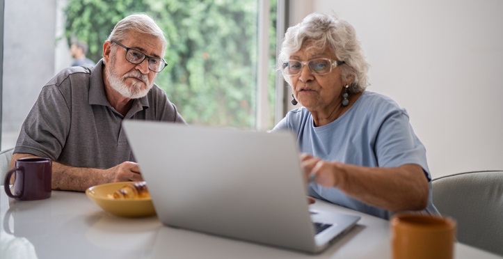 Senior couple talking about home finances and using the laptop at home