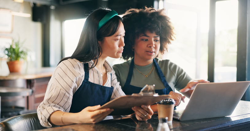 Women, waitress or manager with documents, computer and planning budget in a startup cafe
