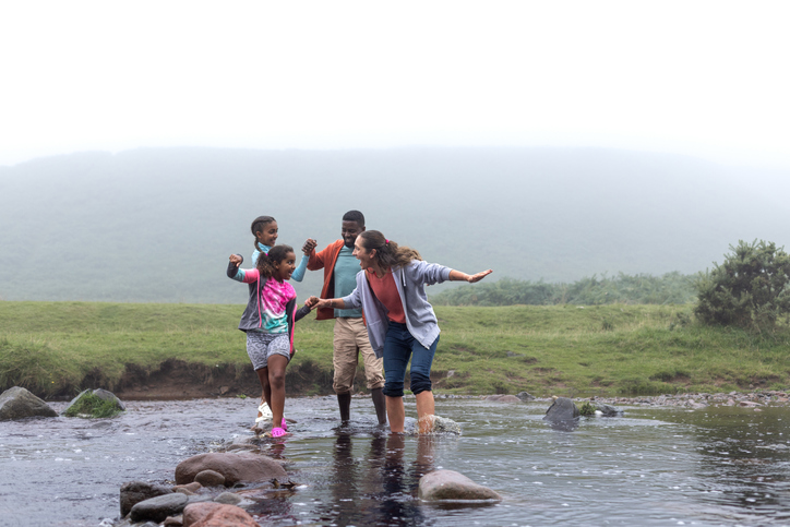 Wide shot of a family walking in a river in Northumberland, North East of England.