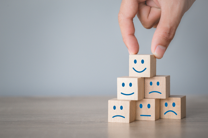 Customer pressing smiley face emoticon on wood cube, Service rating, satisfaction concept.