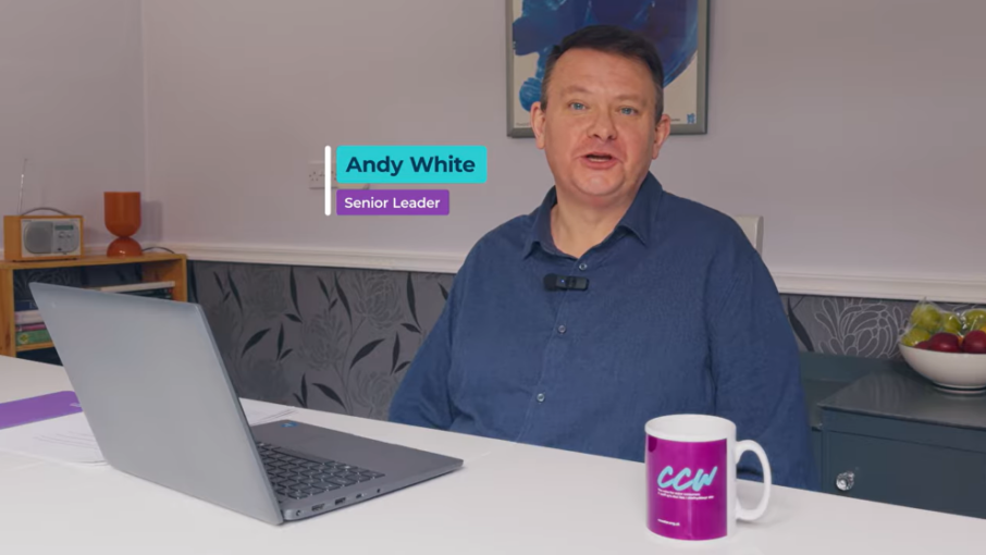 Andy White, Senior Leader. He is sitting with his laptop at the dining table in the home wearing a blue button down shirt.