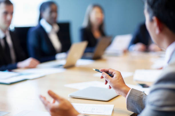 Colleagues in a business meeting sat around a board room conference table.