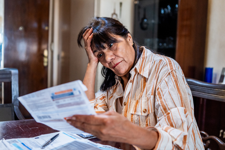 Worried senior woman looking home bills at home