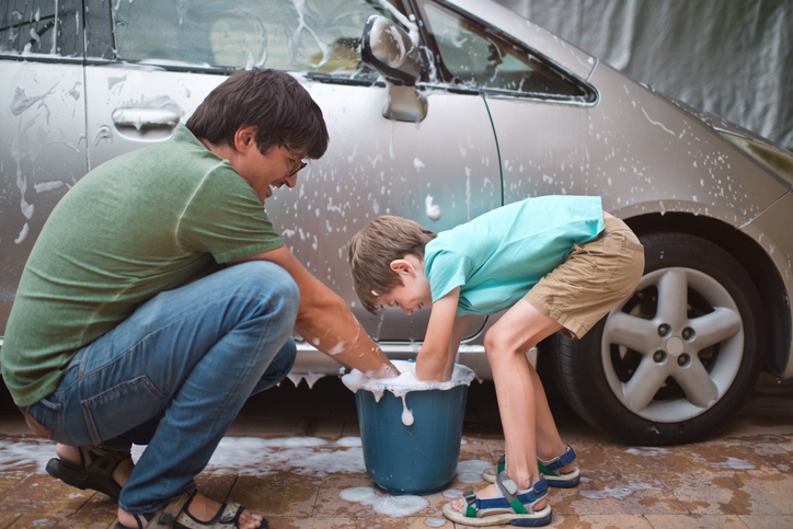Family washing car outdoors in summer evening